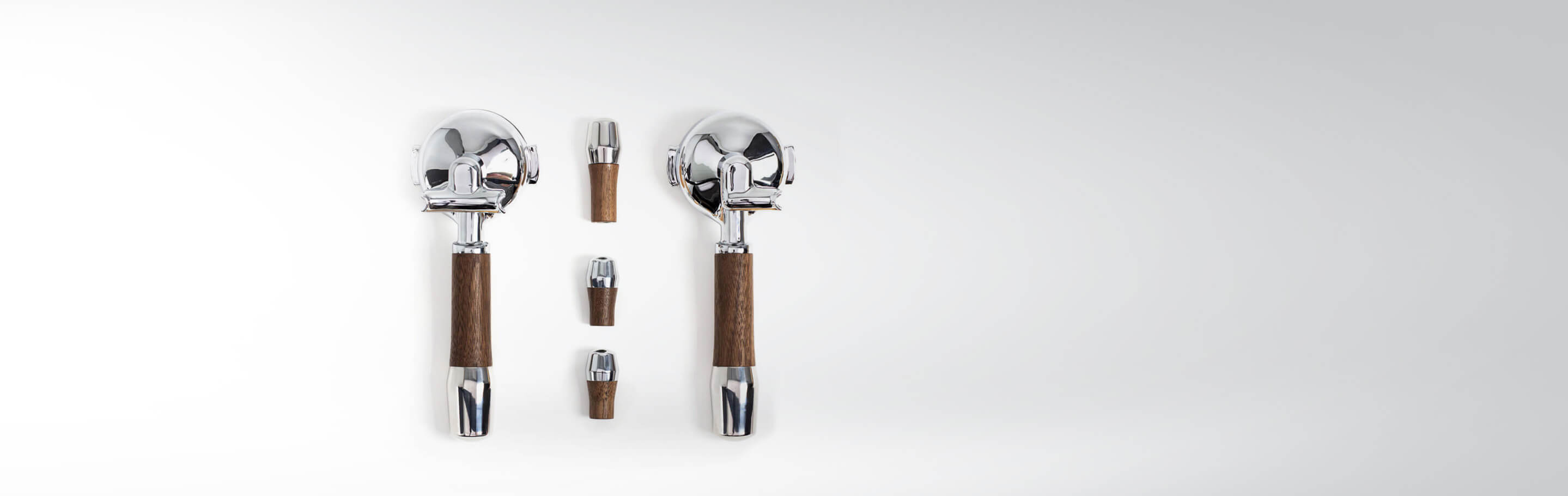 Zwei Kaffeetassendrücker mit Griffen aus Edelstahl und Holzummantelung auf einem weißen Hintergrund