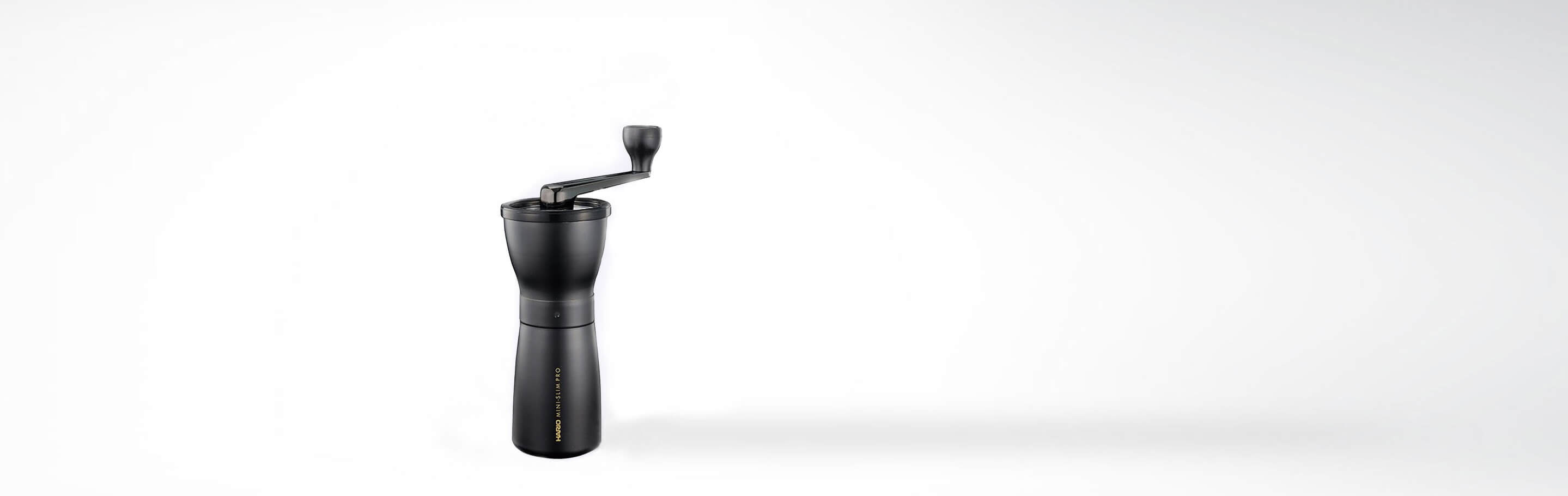 Schwarze Handkaffeemühle mit Kurbel auf weißem Hintergrund