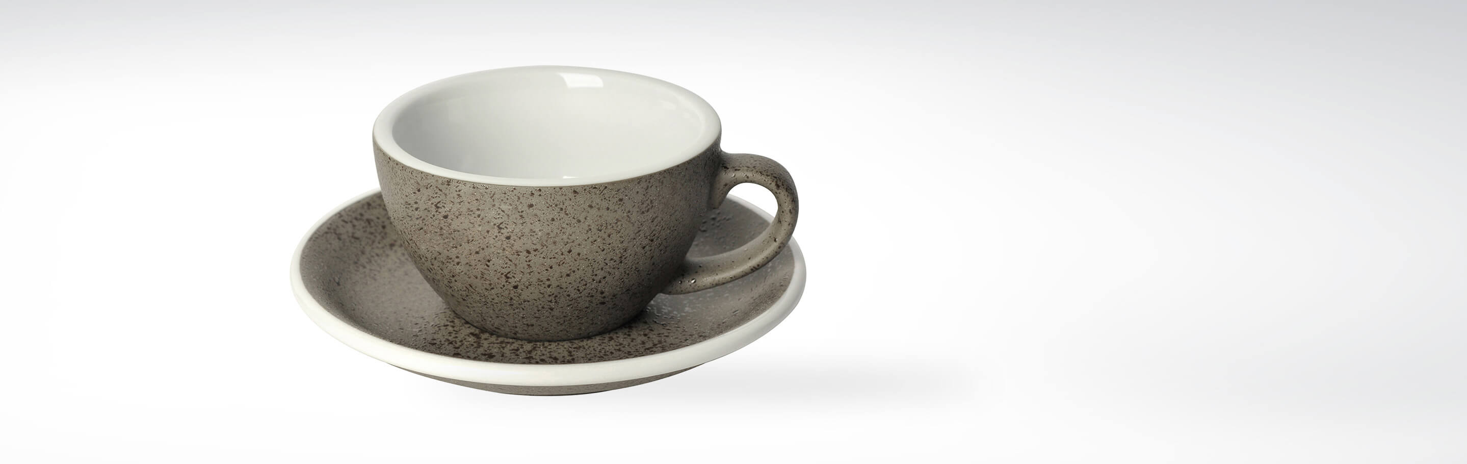 Graue Steinzeug Tasse mit passender Untertasse auf weißem Hintergrund