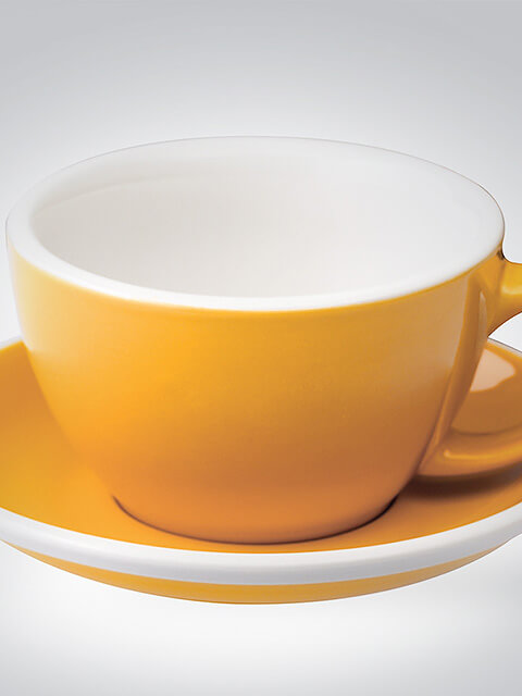 Eine gelbe Kaffeetasse mit passender Untertasse aus Porzellan vor neutralem Hintergrund