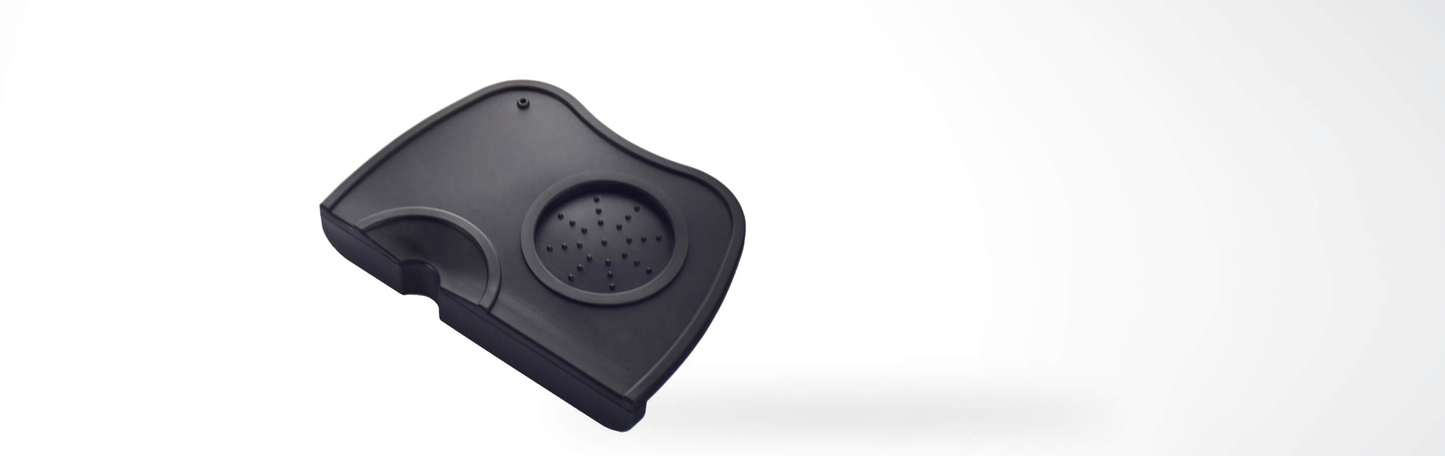 Eine schwarze Silikon-Milchaufschäumstation mit Abtropfgitter auf weißem Hintergrund