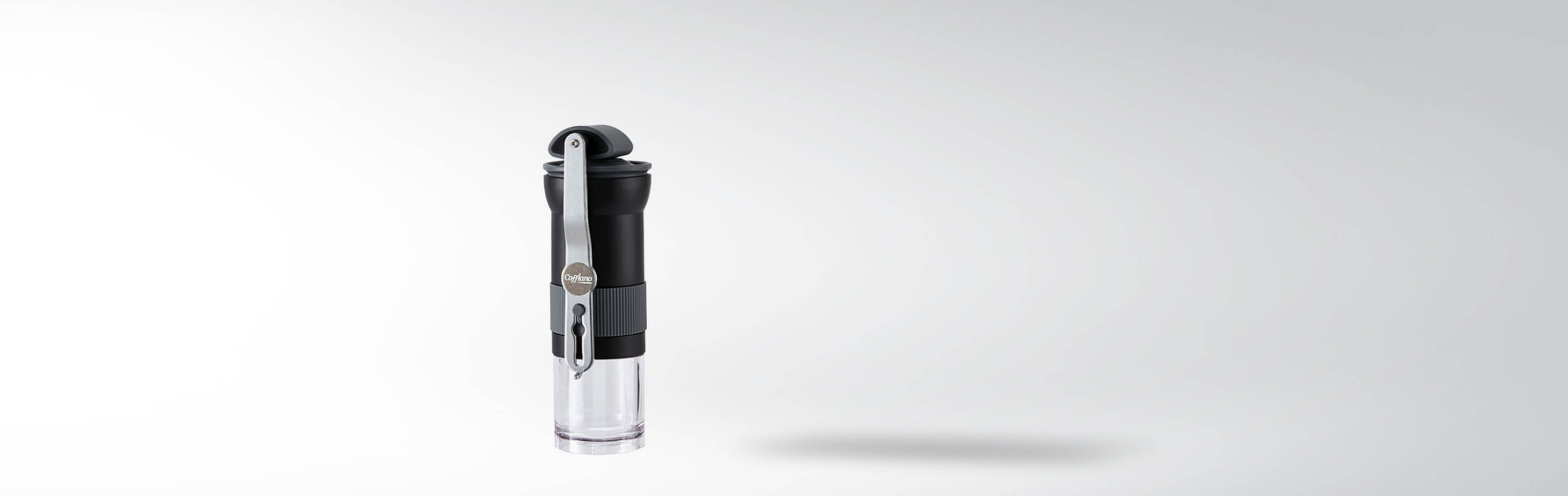 Kompakte Kaffeemühle von Cafflano mit schwarzem Gehäuse und transparentem Behälter vor weißem Hintergrund