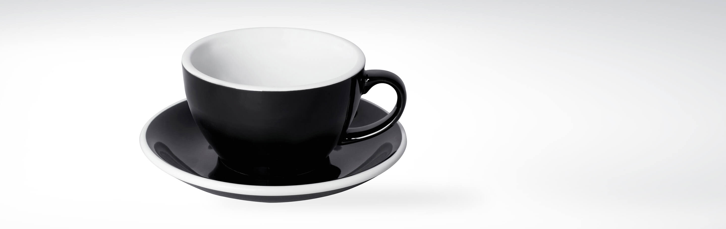 Schwarze Kaffeetasse mit weißem Innenrand auf passender Untertasse