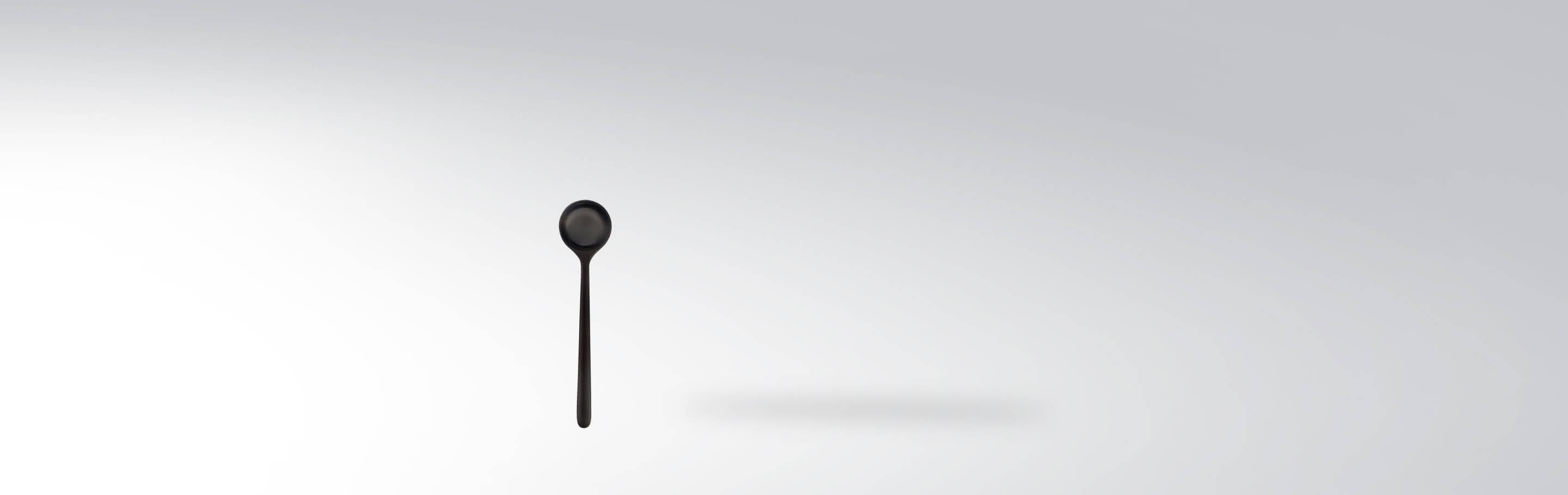 Einzelner schwarzer Teelöffel aus Edelstahl auf neutralem Hintergrund