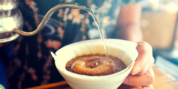 Frisch gebrühter Kaffee im Handfilter Person gießt heißes Wasser in einen Handfilter mit frisch gemahlenem Kaffee