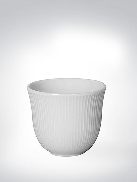 Eleganter weißer Porzellanbecher mit feiner Rillenstruktur vor neutralem Hintergrund