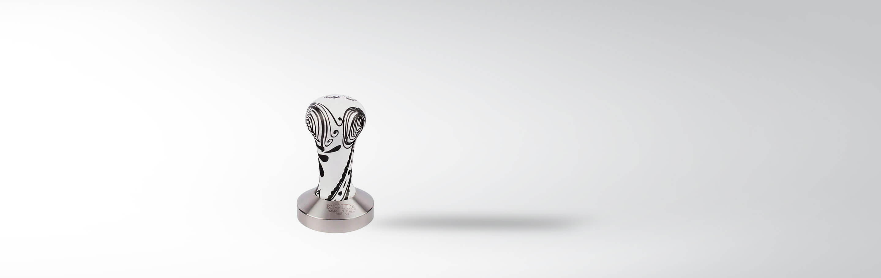 Metallischer Espressotamper mit dekorativem Griff auf hellem Hintergrund