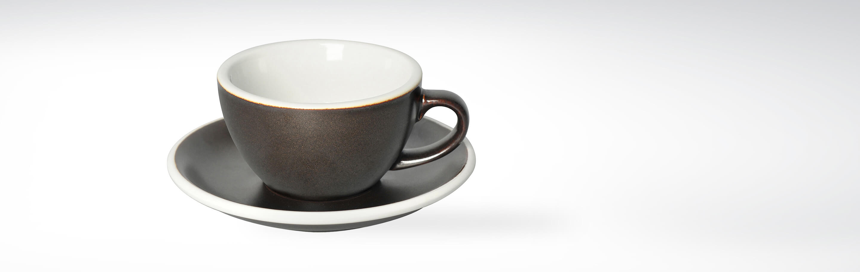 Dunkelbraune Espressotasse mit passender Untertasse auf weißem Hintergrund