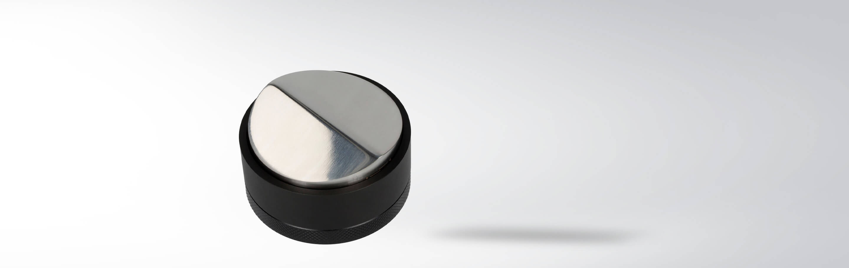 Nahaufnahme eines runden, silbernen Metallknopfs auf grauem Hintergrund