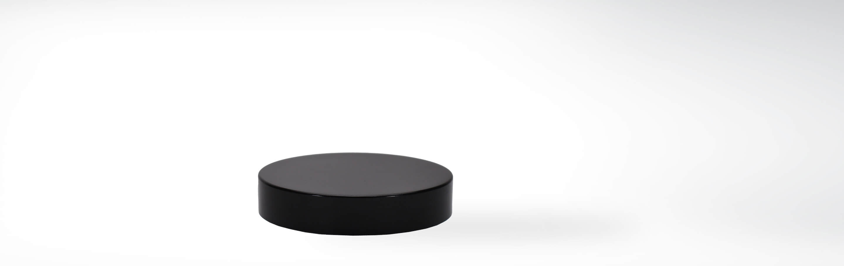 Ein schwarzer runder Deckel, der auf einem weißen Hintergrund liegt