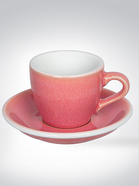 Eine rosa Espressotasse mit passender Untertasse, aus Keramik gefertigt, vor einem neutralen Hintergrund.