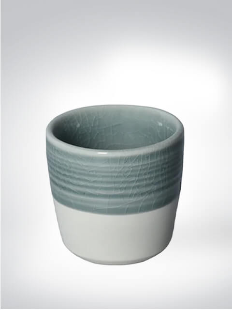 Keramikbecher mit blauer und weißer Glasur auf hellem Hintergrund