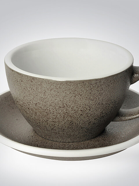 Detailaufnahme einer handgefertigten Keramiktasse mit passender Untertasse in Steinoptik, ideal für Espresso oder Tee.