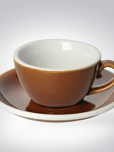 Nahaufnahme einer braunen Keramiktasse mit glänzendem Finish, die auf einer passenden Untertasse steht