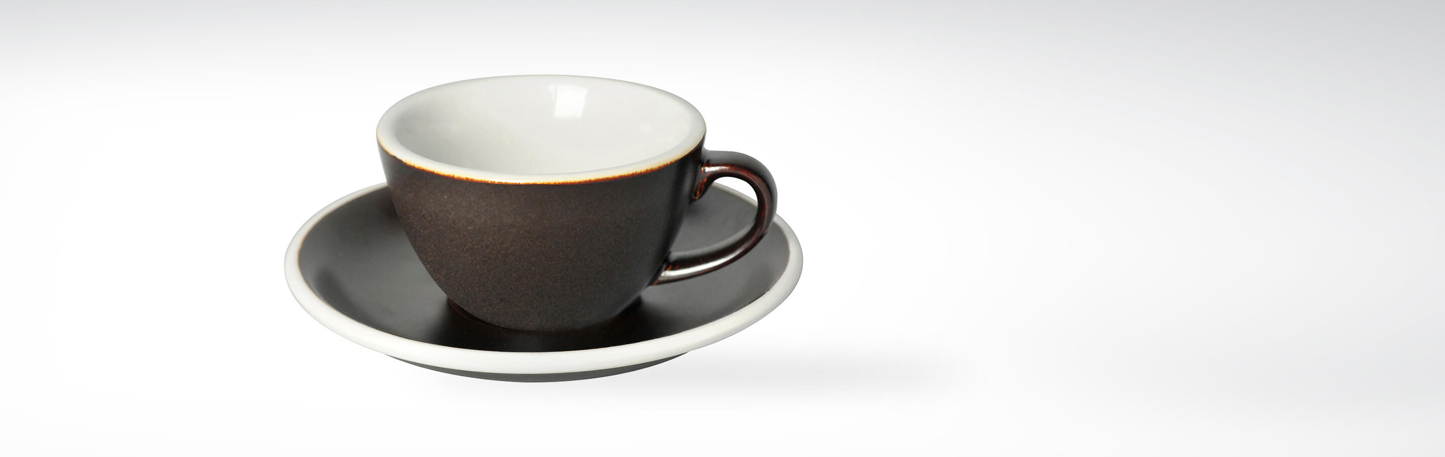 Espressotasse mit Untertasse aus Keramik in Dunkelbraun auf weißem Hintergrund