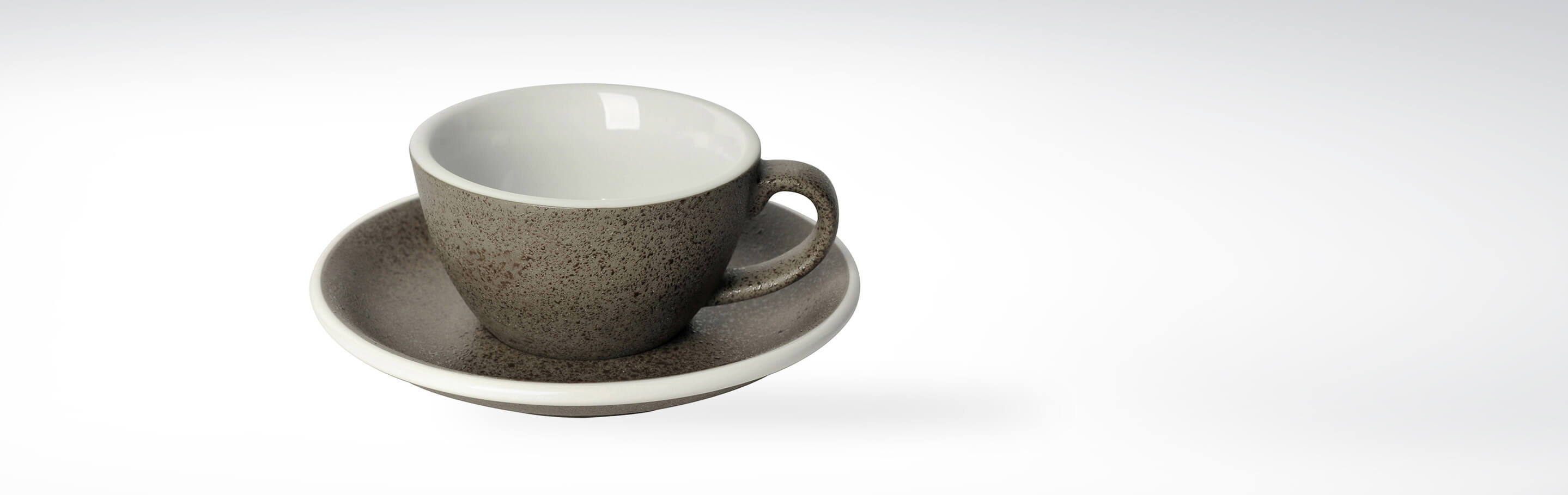 Graue Keramiktasse mit passender Untertasse auf weißem Hintergrund