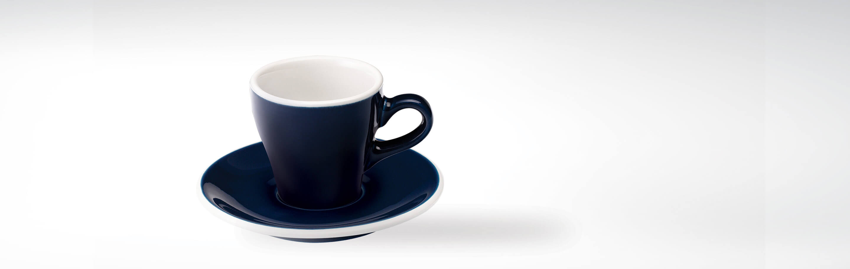 Dunkelblaue Espressotasse mit passender Untertasse auf weißem Hintergrund
