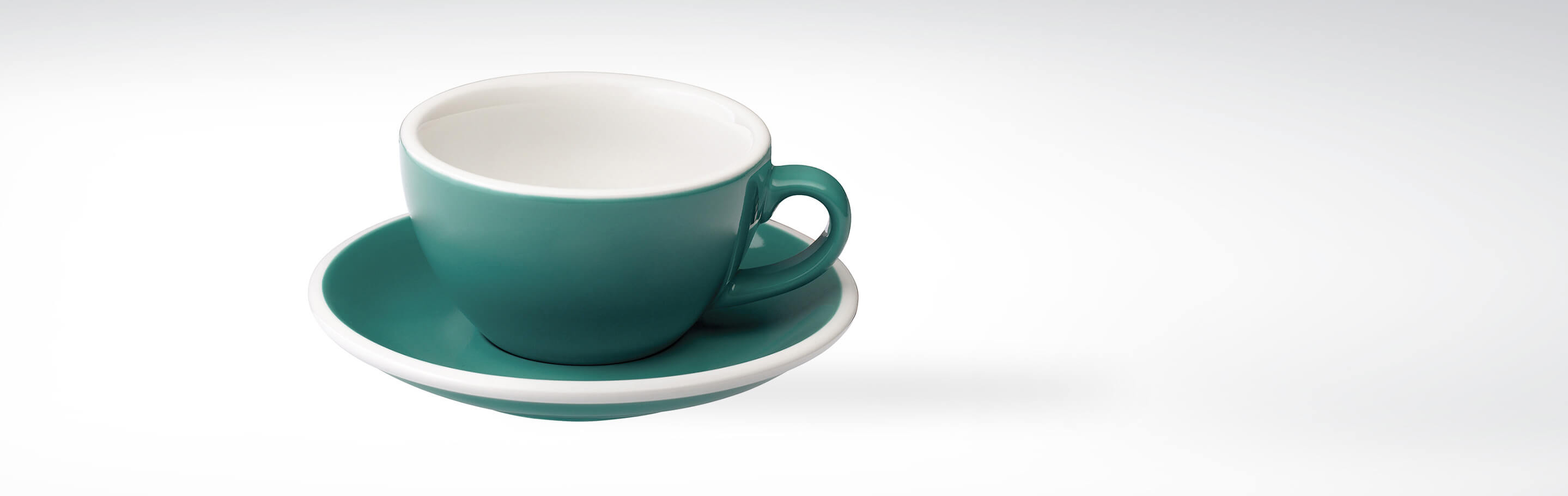 Grüne Tasse mit passender Untertasse vor weißem Hintergrund