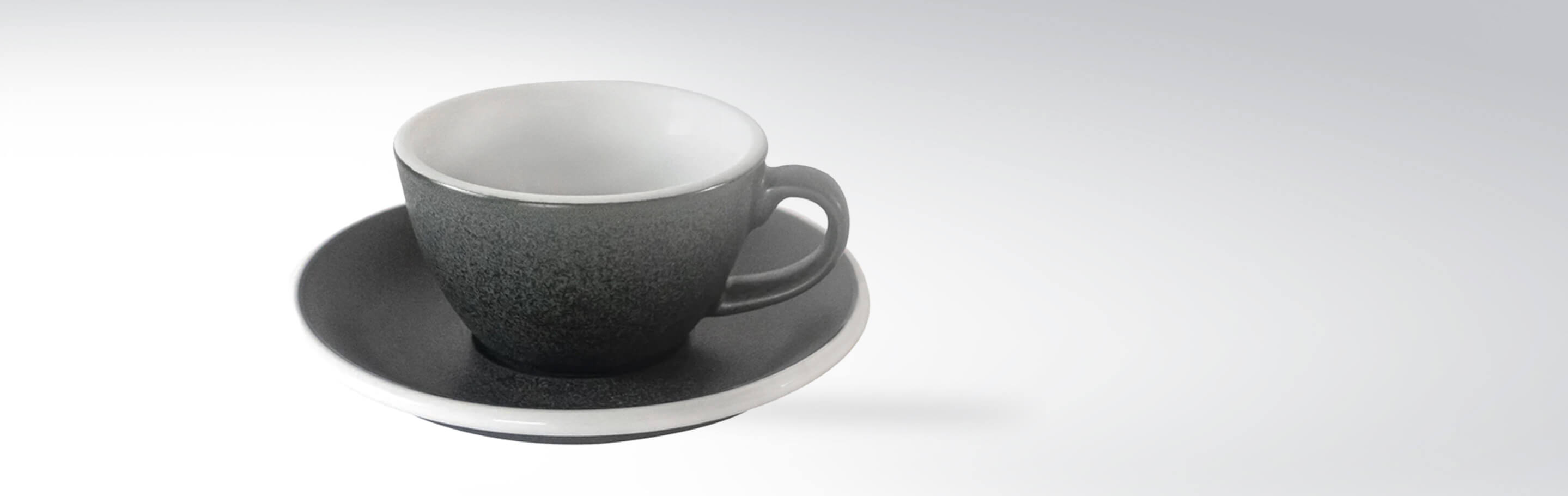 Graue Keramiktasse mit passender Untertasse auf weißem Hintergrund