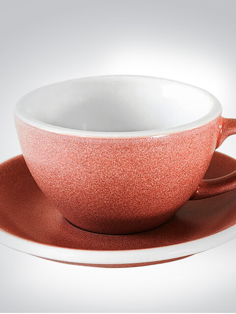 Nahaufnahme einer roten Keramiktasse auf einer passenden Untertasse, ideal für Kaffee oder Tee