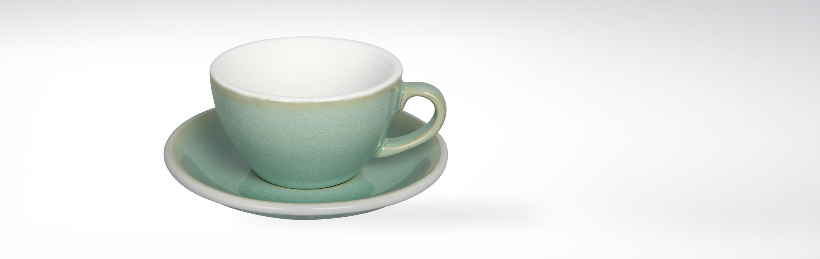 Pastellgrüne Kaffeetasse mit passender Untertasse auf hellem Hintergrund