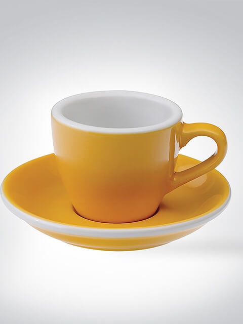 Gelbe Espressotasse mit Untertasse aus Keramik vor grauem Hintergrund