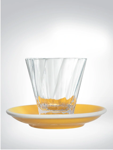 Transparente Glastasse auf gelber Untertasse