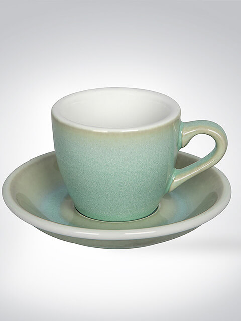 Keramiktasse mit passender Untertasse in sanftem Grünton auf weißem Hintergrund