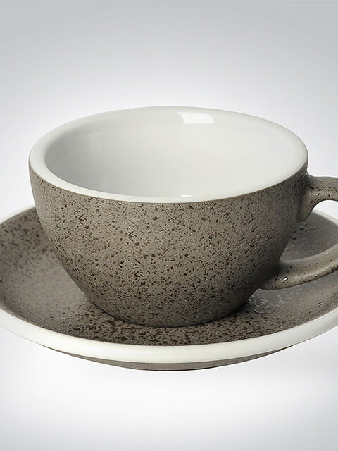 Graue Keramiktasse mit passender Untertasse, handgefertigt in Steinoptik, auf neutralem Hintergrund