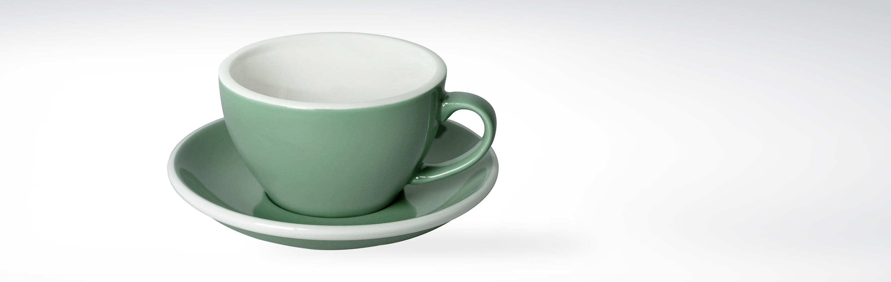 Grüne Keramiktasse mit Untertasse auf weißem Hintergrund