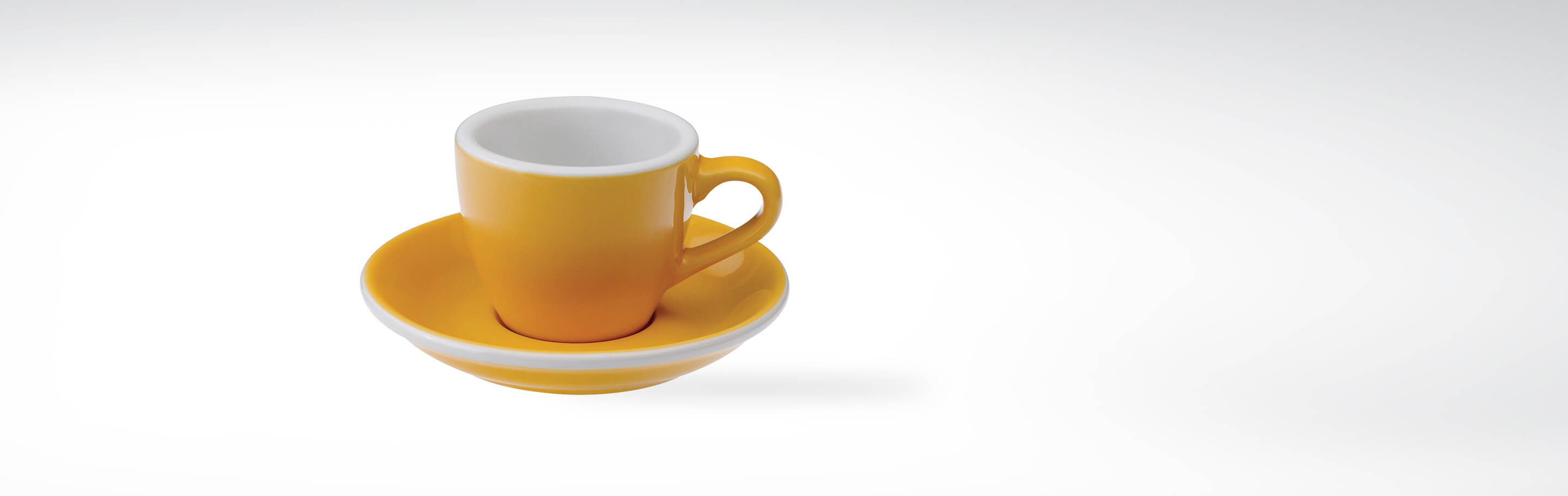 Gelbe Espressotasse mit passender Untertasse aus Keramik auf weißem Hintergrund