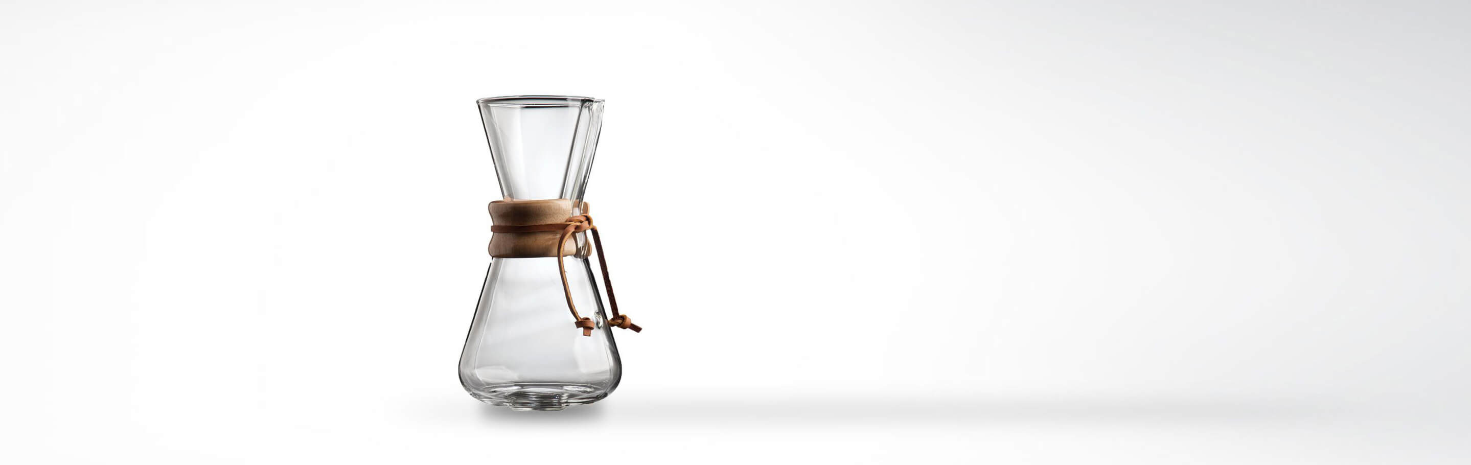 Transparente Glaskaraffe mit einem Holzmantel und Lederband auf weißem Hintergrund