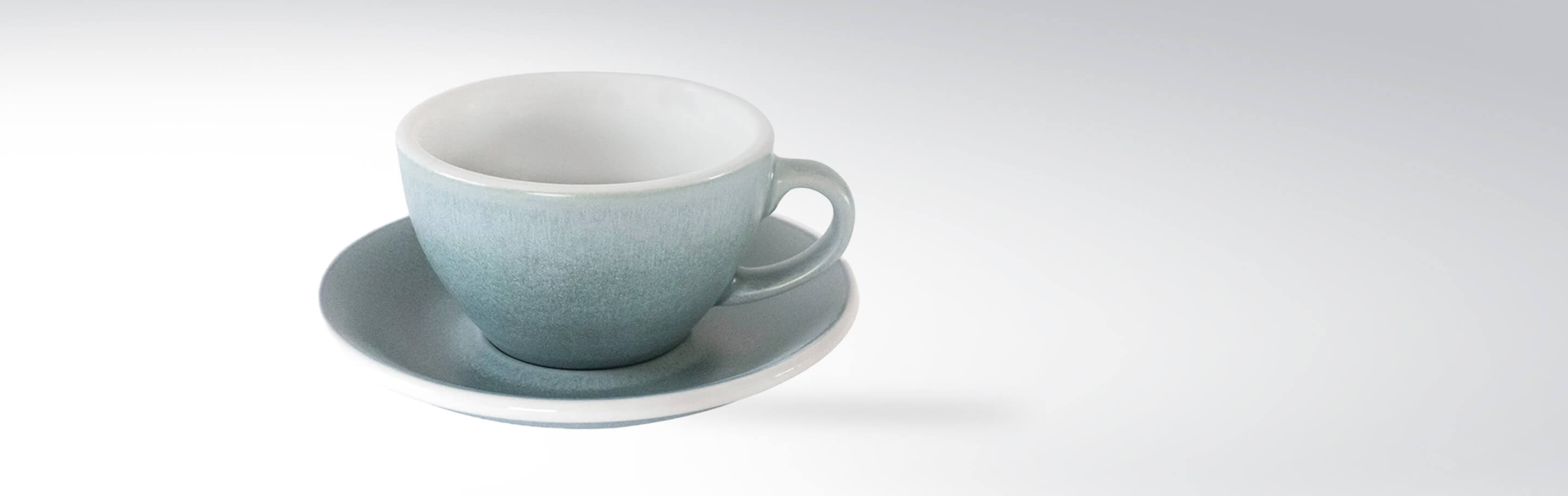 Graue Keramik-Tasse mit passender Untertasse auf weißem Hintergrund