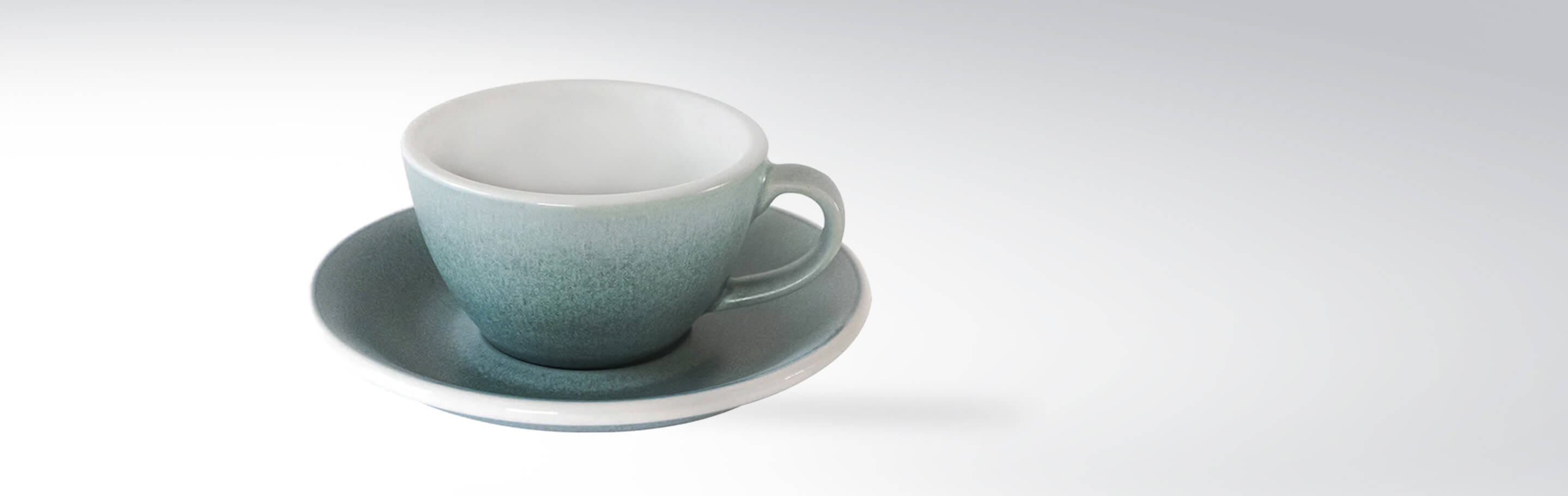 Keramik-Kaffeetasse mit Untertasse in einem sanften Grünton auf hellem Hintergrund