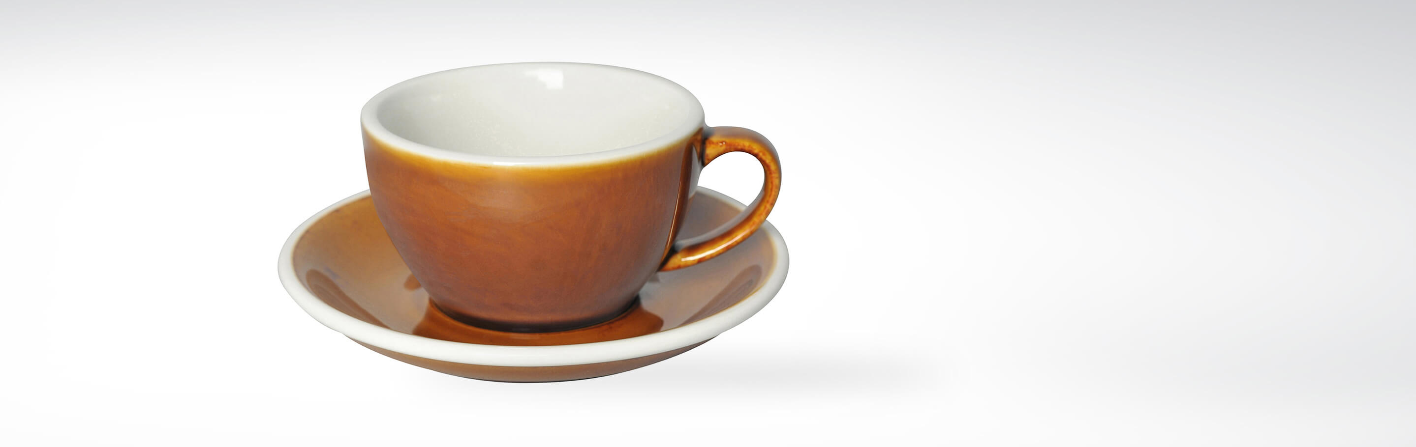 Braune Keramik-Espressotasse mit passender Untertasse auf weißem Hintergrund