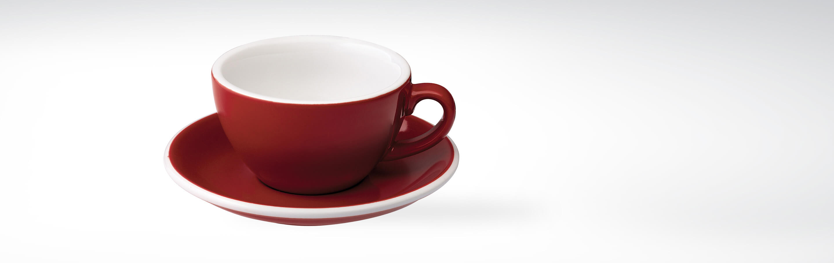 Rote Tasse mit passender Untertasse auf weißem Hintergrund