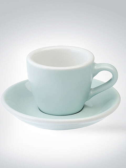 Kleine Espressotasse mit dazu passender Untertasse in sanftem Pastellgrün auf hellem Hintergrund