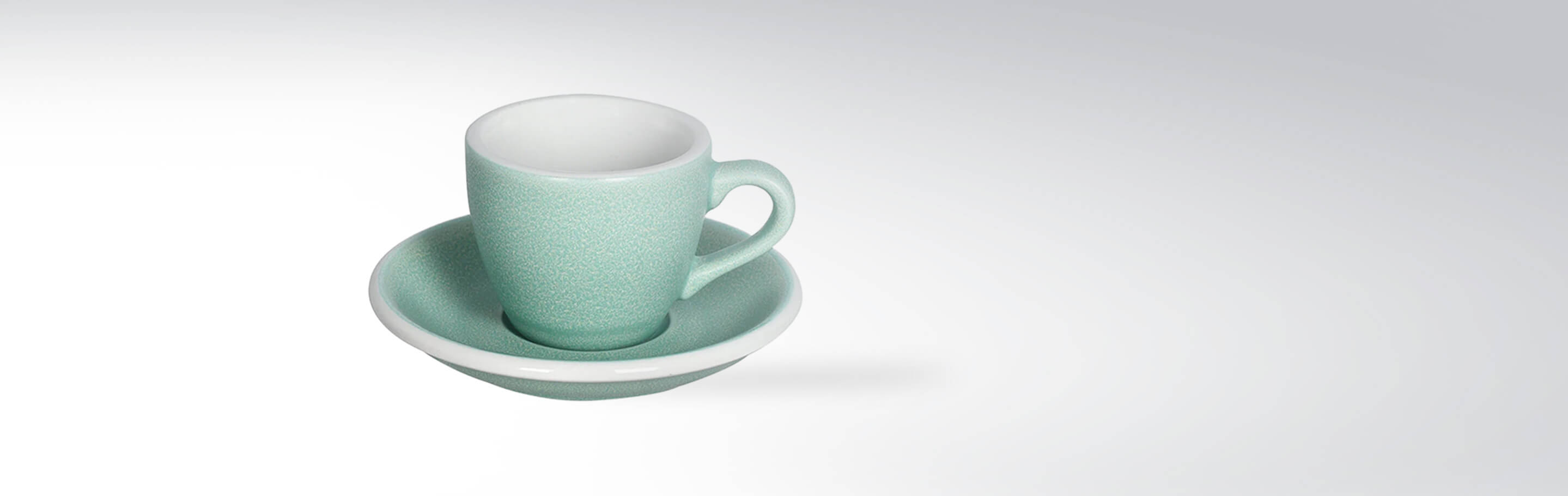 Grüne Espressotasse mit Unterteller auf weißem Hintergrund