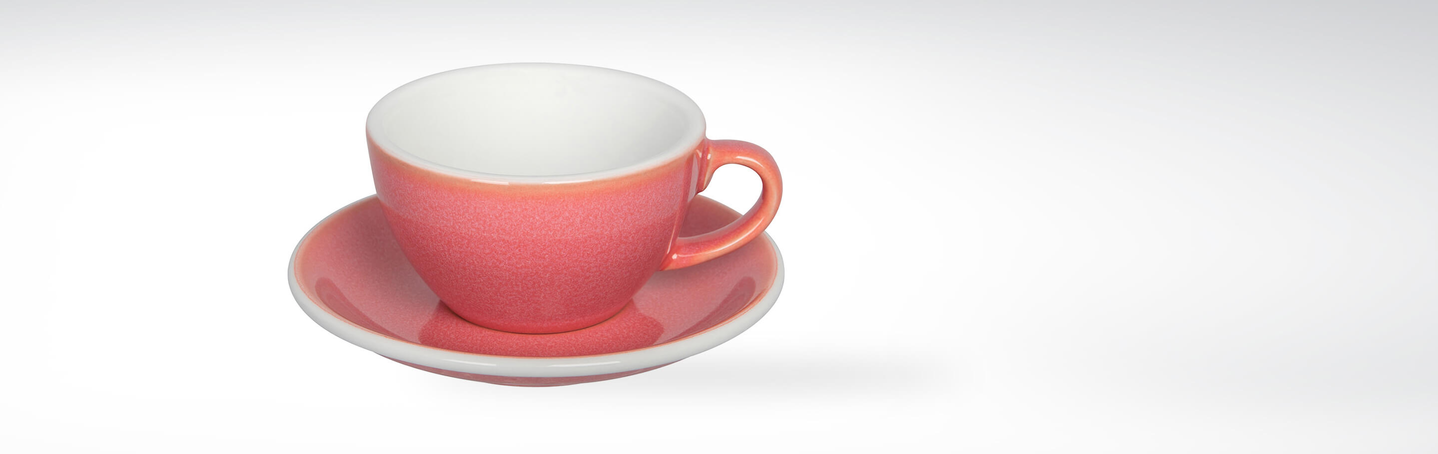 Rote Keramiktasse mit passender Untertasse auf weißem Hintergrund