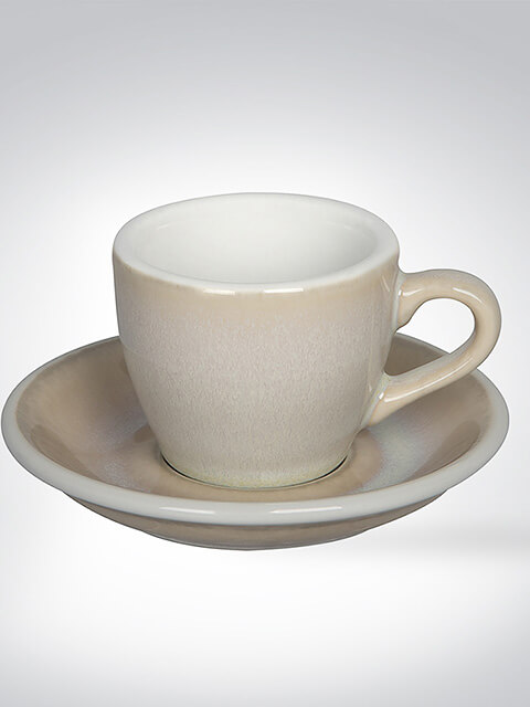 Beige Kaffeetasse mit passender Untertasse vor neutralem Hintergrund