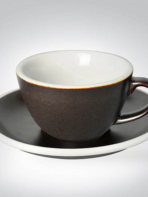 Eine schwarze Keramiktasse mit weißem Innenraum auf passender Untertasse.