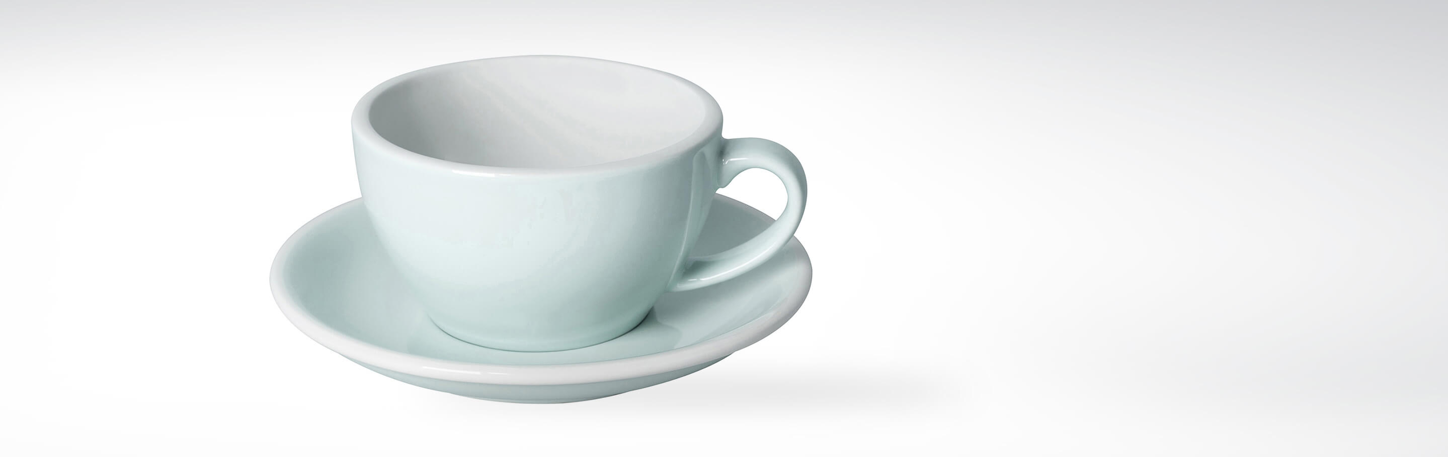 Keramiktasse mit Untertasse in mintgrün vor weißem Hintergrund