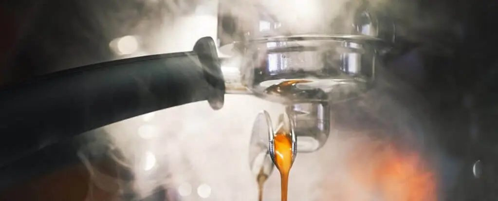 Espresso fließt aus einer Espressomaschine, umgeben von Dampf