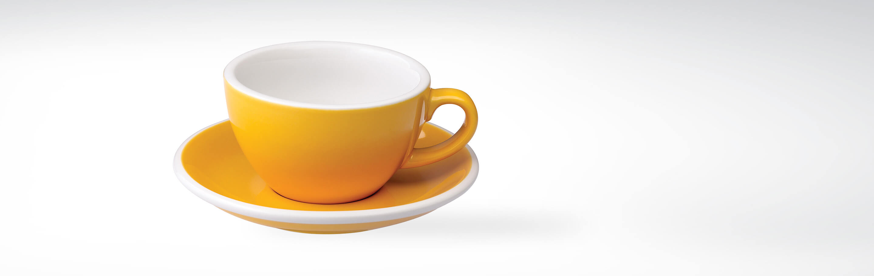 Gelbe Kaffeetasse mit Untertasse aus Keramik auf weißem Hintergrund