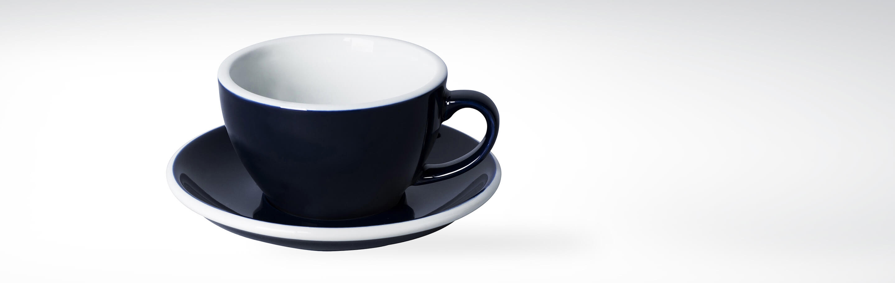 Schwarze Porzellantasse mit passender Untertasse auf hellem Hintergrund