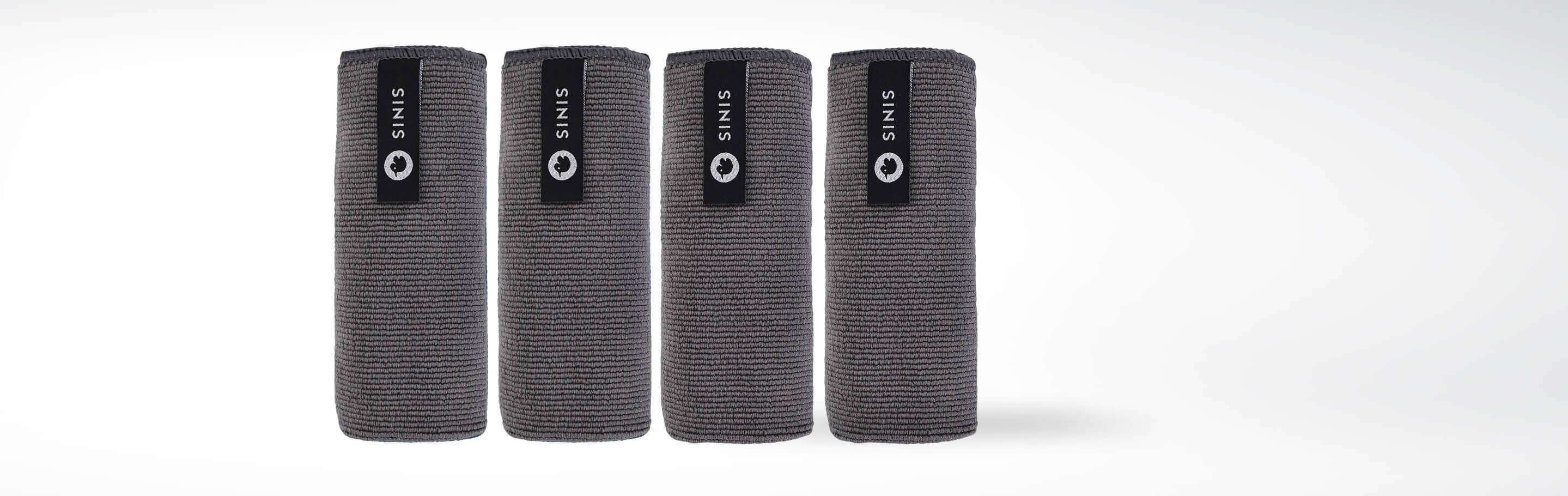 Vier schwarze, zusammengerollte SIENIS-Matten für Yoga oder Pilates auf weißem Hintergrund