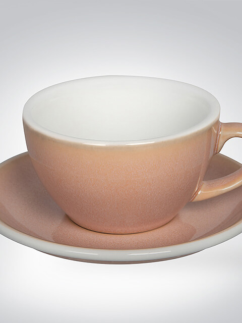 Pastellrosa Keramiktasse mit passender Untertasse, perfekt für Kaffeespezialitäten.