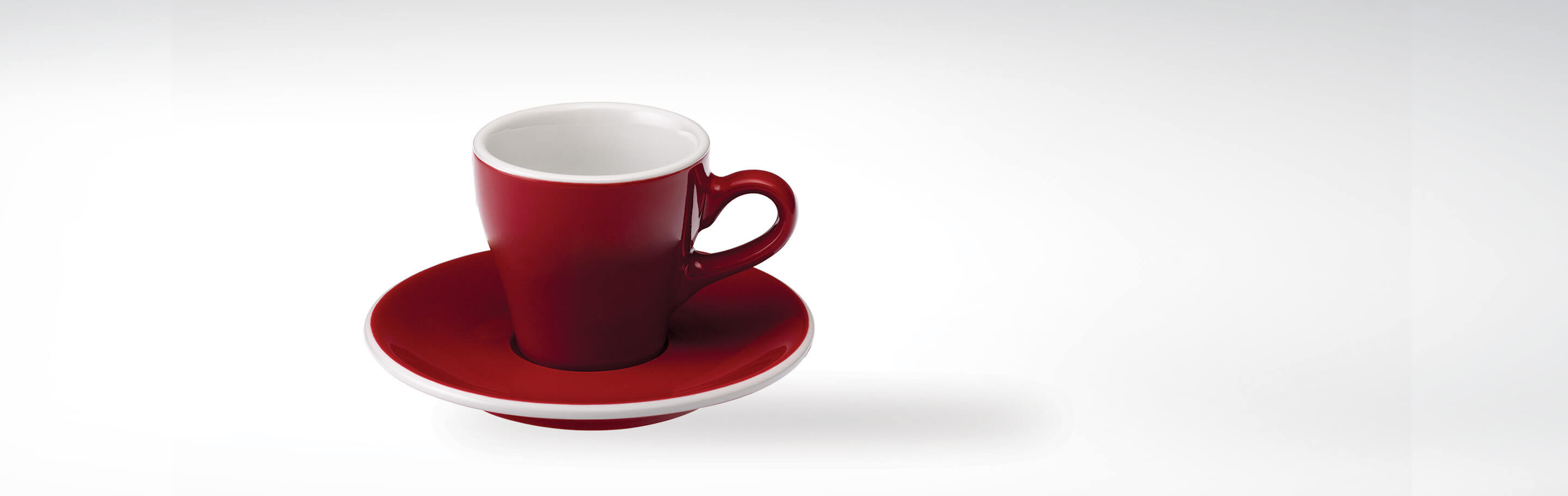 Rote Espressotasse mit passender Untertasse auf weißem Hintergrund