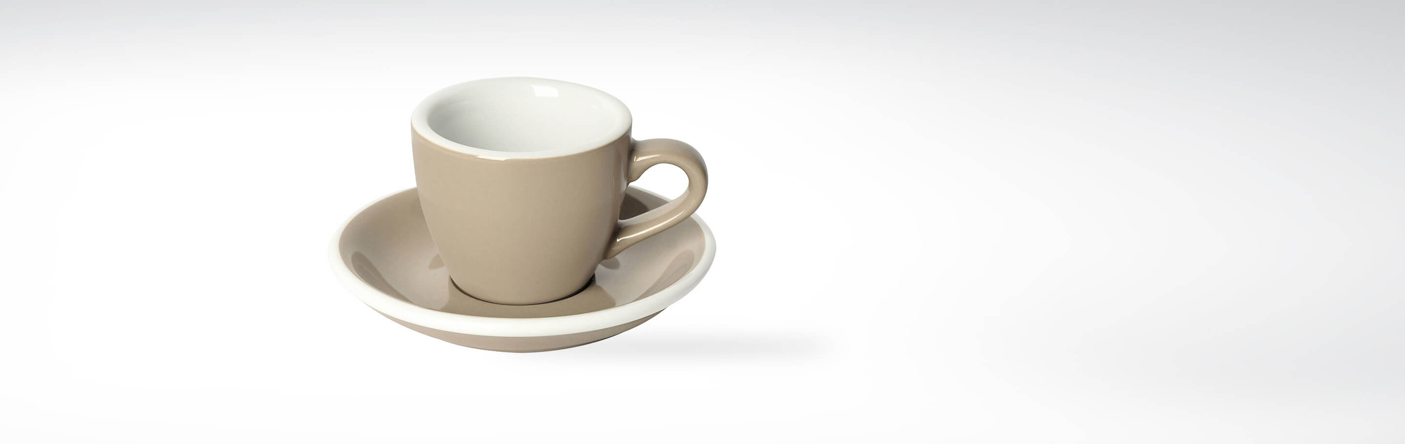 Beige Espressotasse mit passendem Unterteller auf weißem Hintergrund