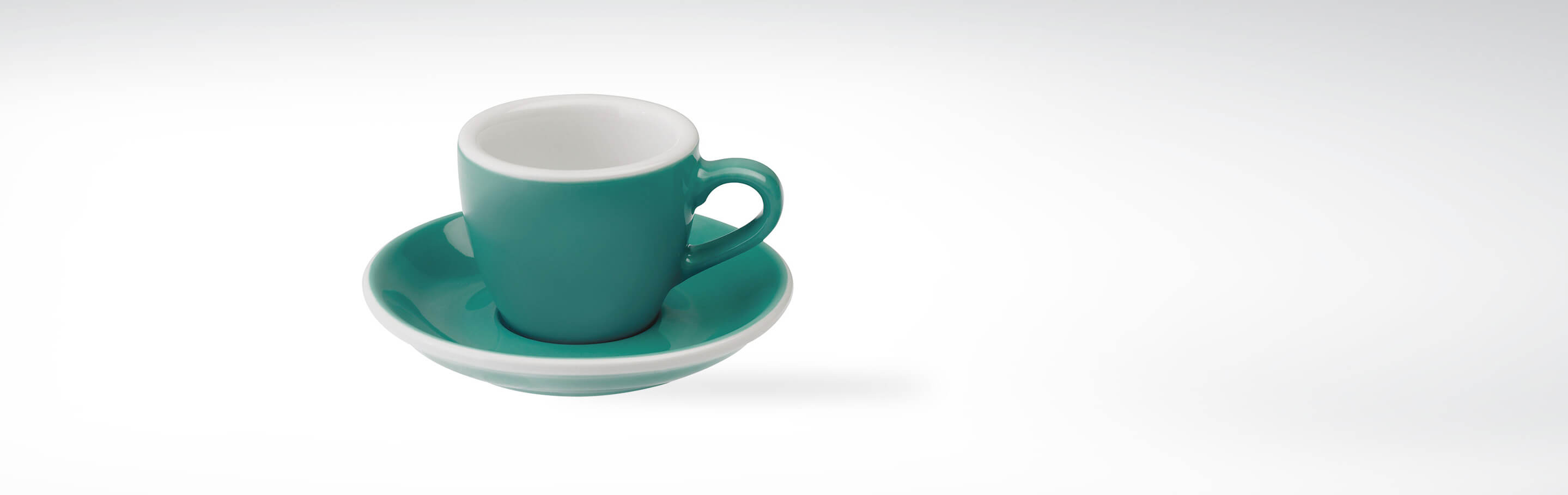 Eine türkise Espressotasse mit passender Untertasse auf weißem Hintergrund